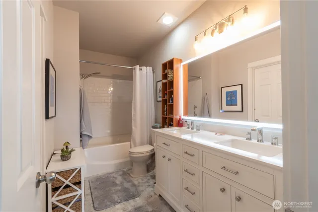a bathroom with a double vanity sink toilet mirror and bathtub