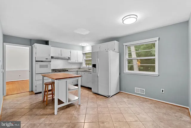 a kitchen with a refrigerator a stove a microwave and a dining table