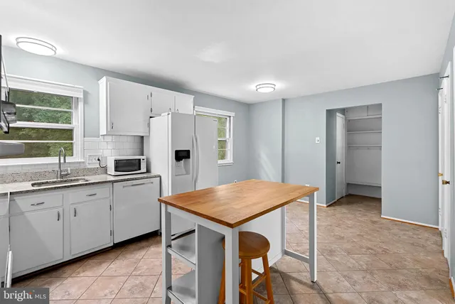 a kitchen with stainless steel appliances granite countertop a kitchen island a stove a refrigerator and a sink