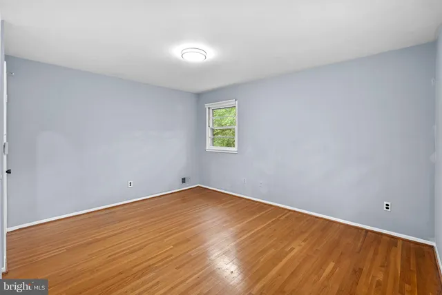 a view of an empty room with wooden floor and window
