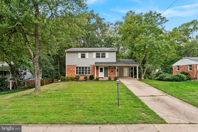 a view of a house with a big yard plants and large trees
