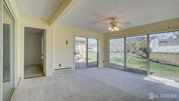 an empty room with chandelier fan and windows