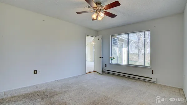 an empty room with chandelier fan and windows