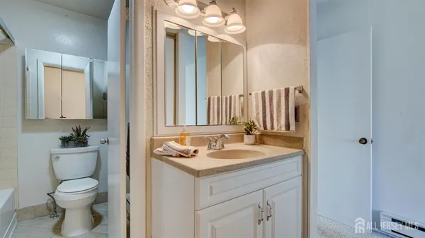 a bathroom with a granite countertop sink a toilet and a mirror