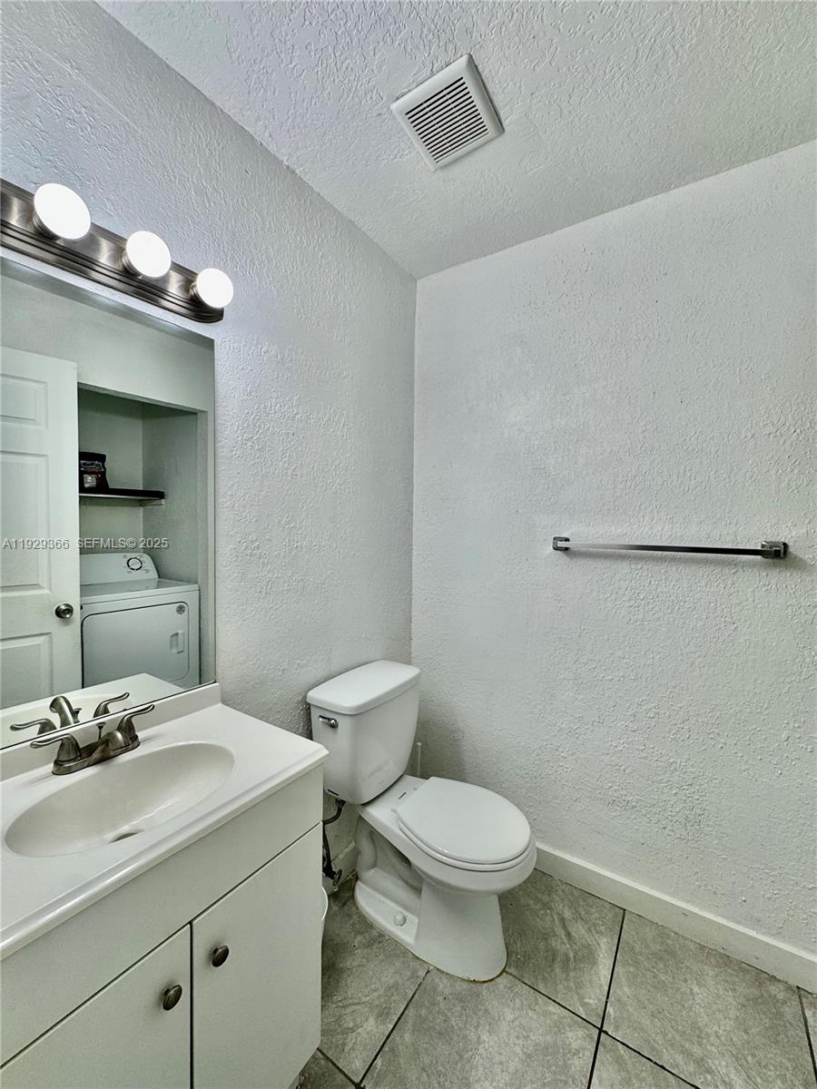 22205 Southwest 103rd Avenue, Unit 22205 Cutler Bay, FL 33190 - Photo 3 of 16 a bathroom with a toilet a sink and mirror
