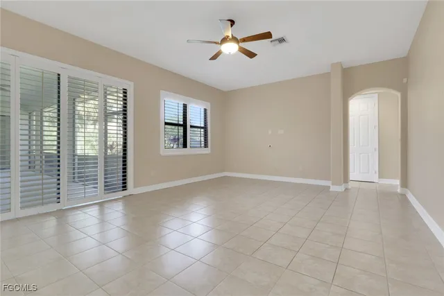 an empty room with chandelier fan and windows