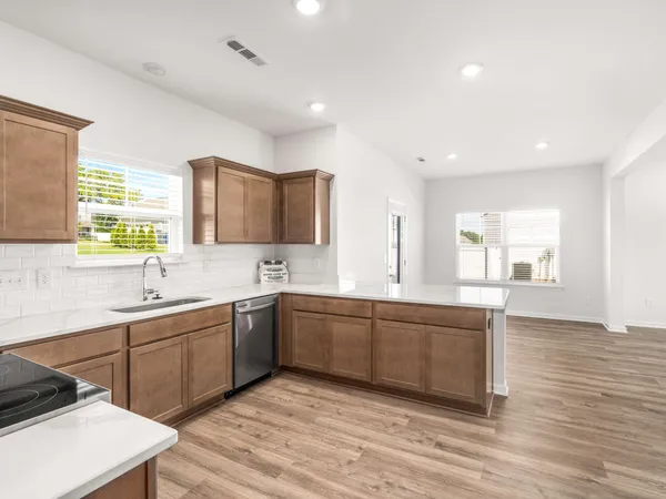 a large kitchen with stainless steel appliances granite countertop a sink dishwasher a stove and a refrigerator with wooden floor