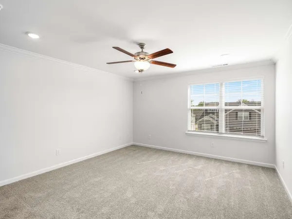 an empty room with chandelier fan and windows