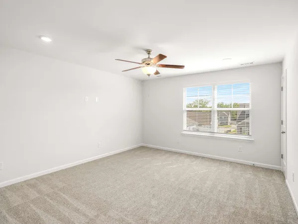 an empty room with a window and a ceiling fan