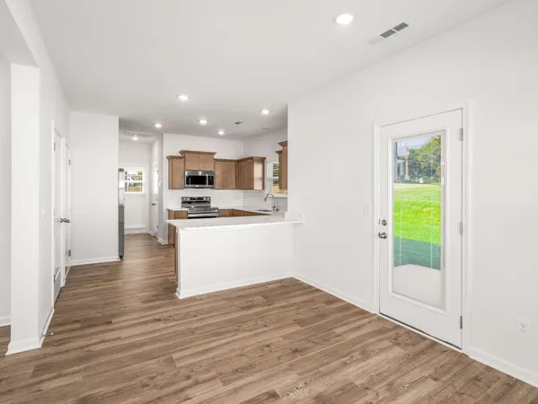a view of kitchen with kitchen island wooden floors appliances and cabinets