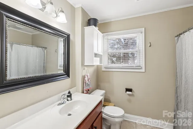 a bathroom with a toilet a sink a mirror and a window