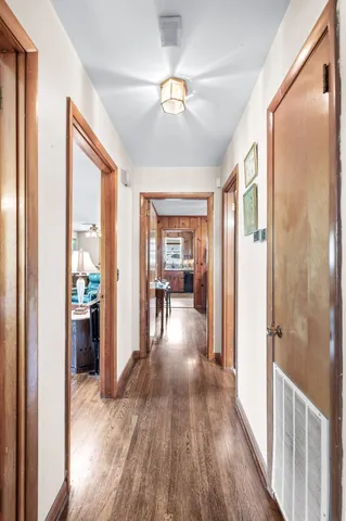 a view of a hallway to a livingroom with wooden floor and a ceiling fan