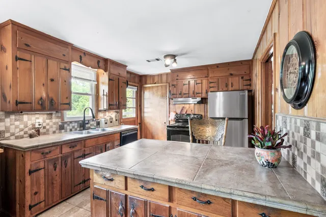 a kitchen with stainless steel appliances granite countertop a sink a stove and a wooden floors