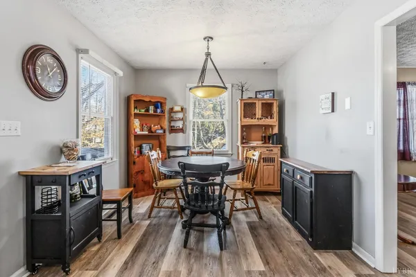 a dining room with wooden floor a chandelier a wooden table and chairs