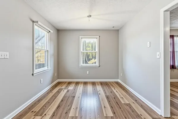 a view of wooden floor in an empty room with a window