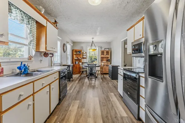 a kitchen with a refrigerator a sink dishwasher a dining table and chairs with wooden floor