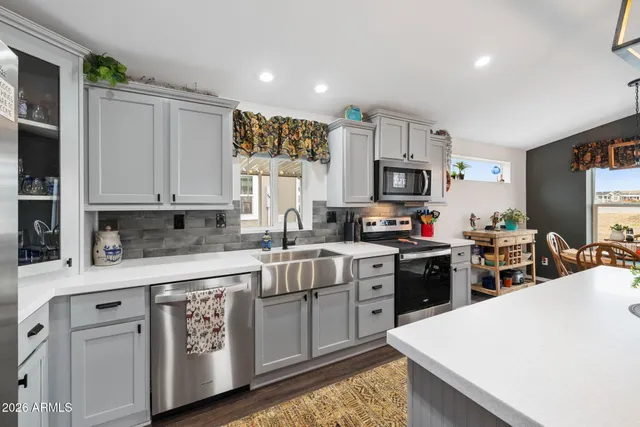 a kitchen with stainless steel appliances granite countertop a stove top oven a sink dishwasher and a refrigerator with wooden floor