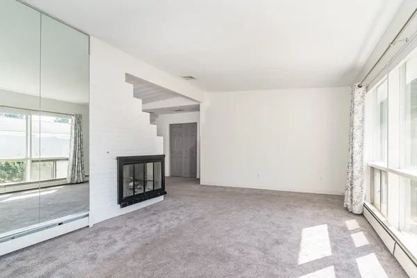 a view of an empty room with a fireplace and a window