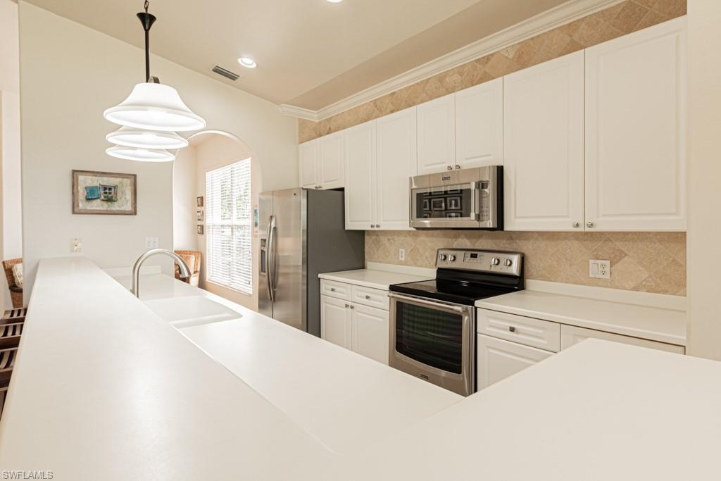 1965 Crestview Way, Unit 156 Naples, FL 34119 - Photo 11 of 45 a kitchen with stainless steel appliances granite countertop a stove top oven a refrigerator a kitchen island a sink and a white cabinets