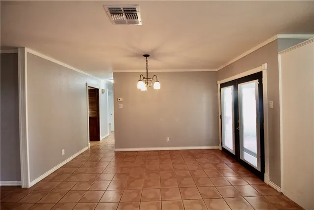 a view of an empty room with window and chandelier fan