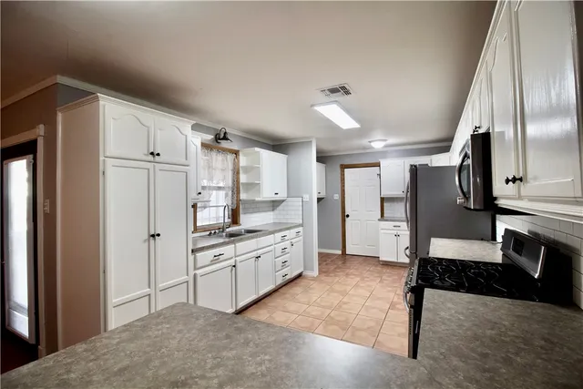 a large kitchen with stainless steel appliances granite countertop a refrigerator and a stove