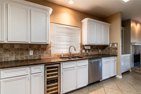 a kitchen with granite countertop white cabinets stainless steel appliances a sink and a window