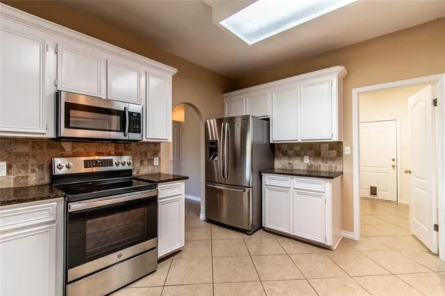 a kitchen with granite countertop a stove microwave and refrigerator