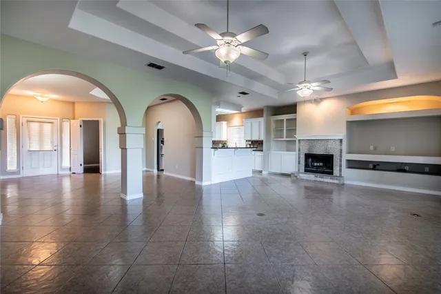 a view of empty room with a fireplace and a chandelier fan
