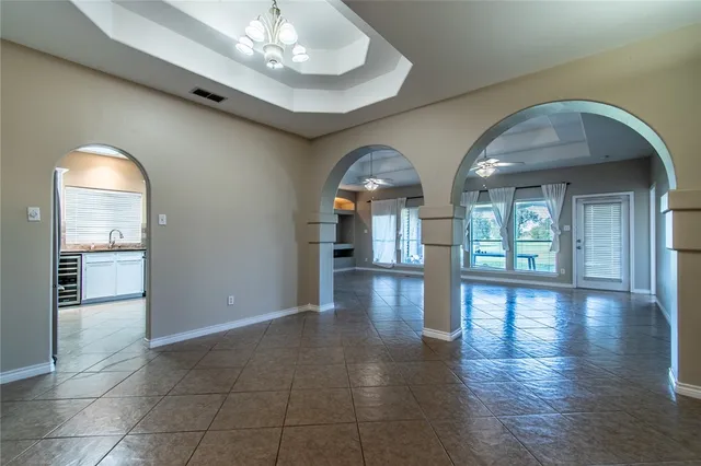 a view of empty room with wooden floor and kitchen view