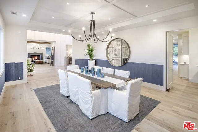 a living room with couches chandelier cabinets and a wooden floor