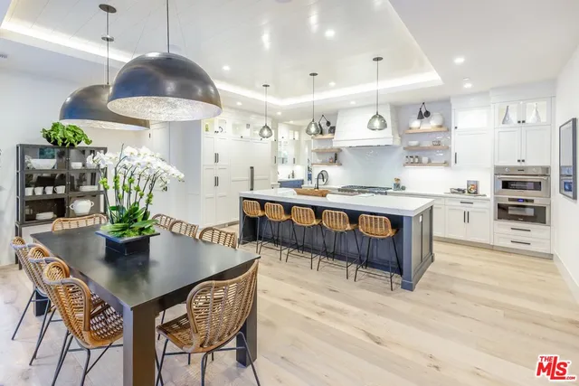 a dining room with stainless steel appliances kitchen island granite countertop a table chairs and a refrigerator