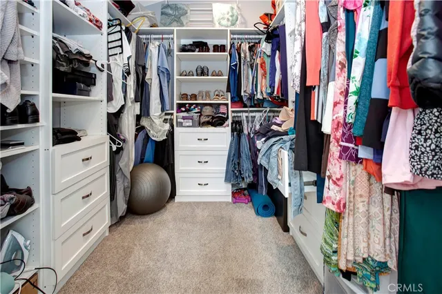 a view of walk in closet with clothes and shoes