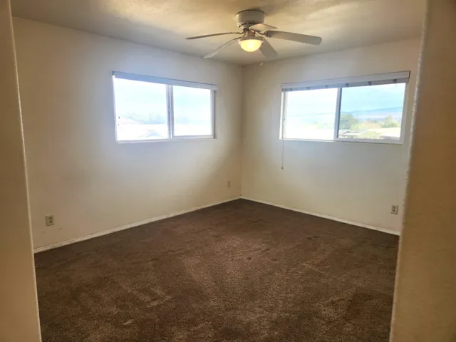 an empty room with a window and a fan