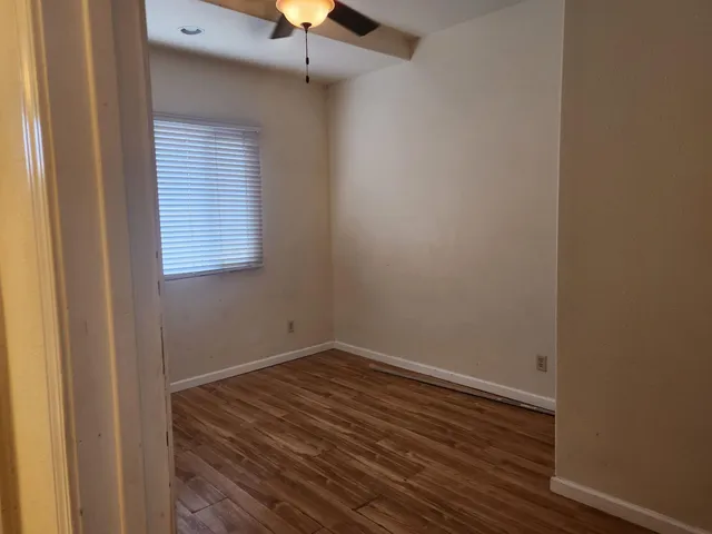an empty room with a window and wooden floor