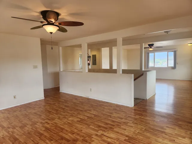 a view of an empty room with wooden floor and a window