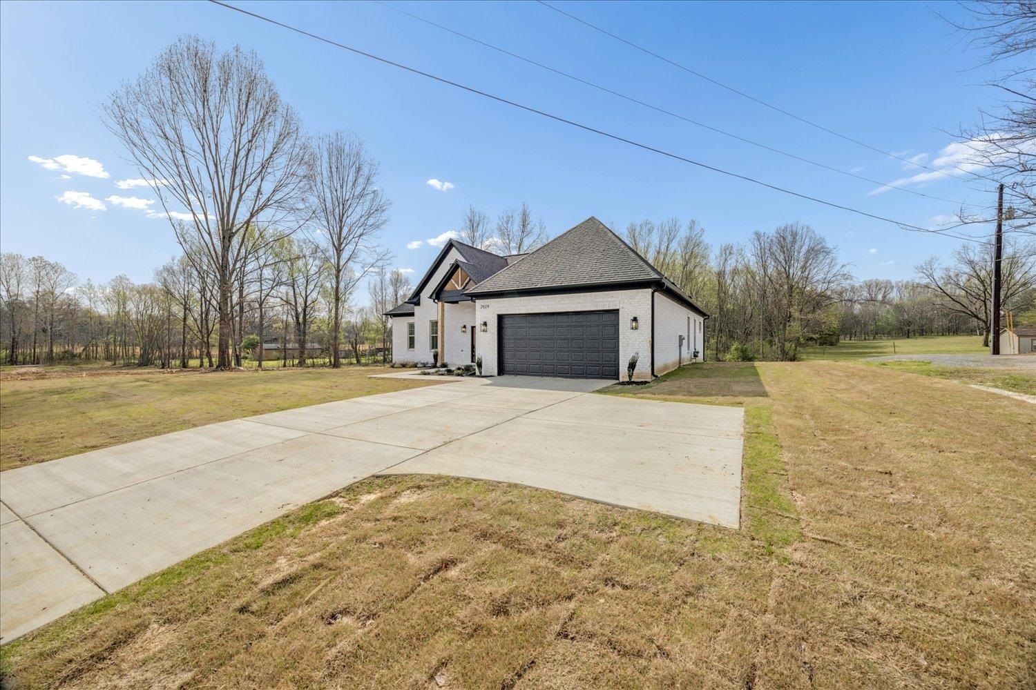 2939 Brighton-Clopton Road Brighton, TN 38011 - Photo 33 of 36 View of home's exterior with a yard, driveway, a garage, brick siding, and a shingled roof