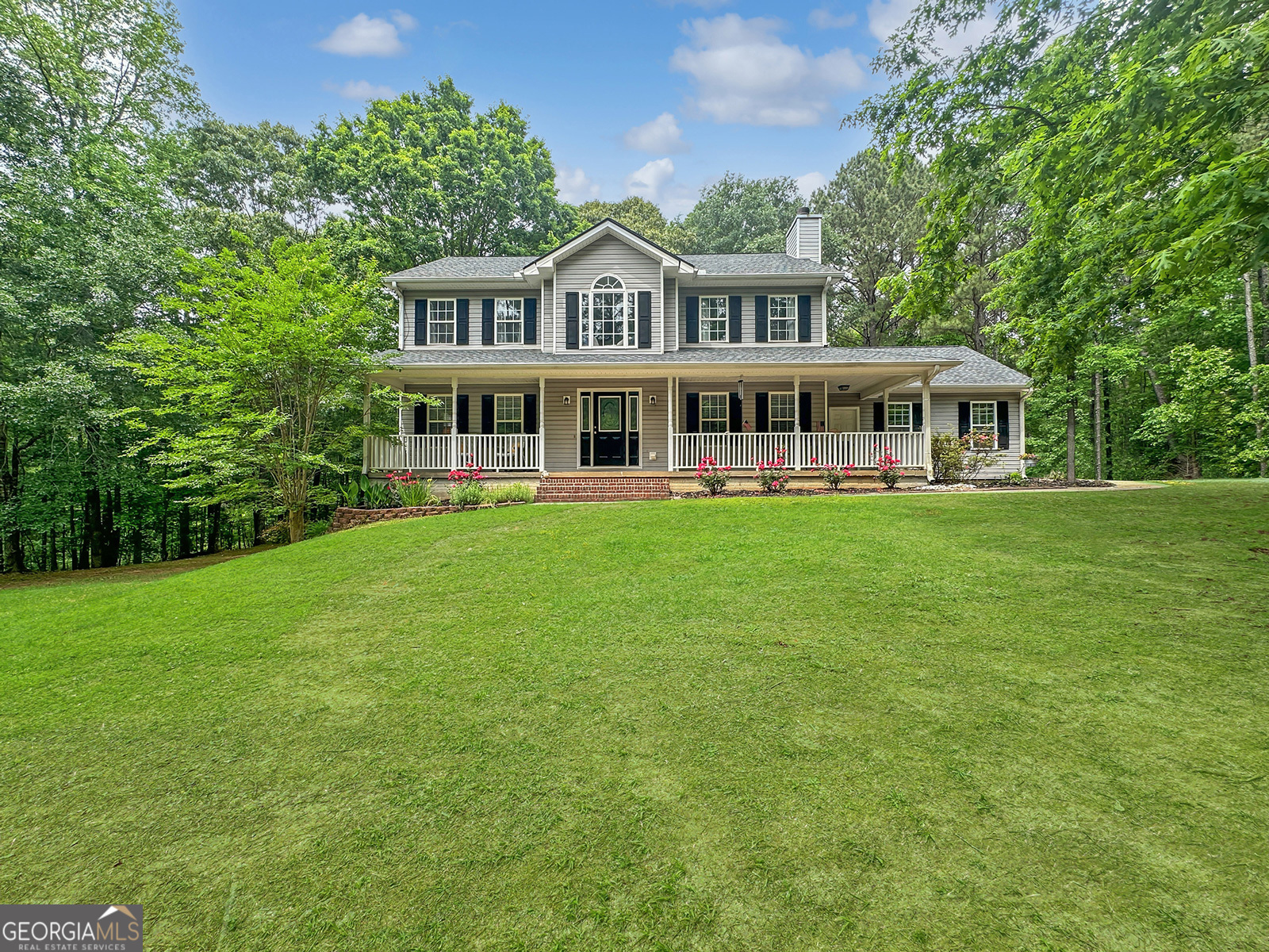 a front view of a house with a garden and trees