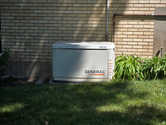 871 Bonita Way Centerville, UT 84014 - Photo 61 of 61 Generac whole-house generator on a concrete pad, positioned against a light brick exterior