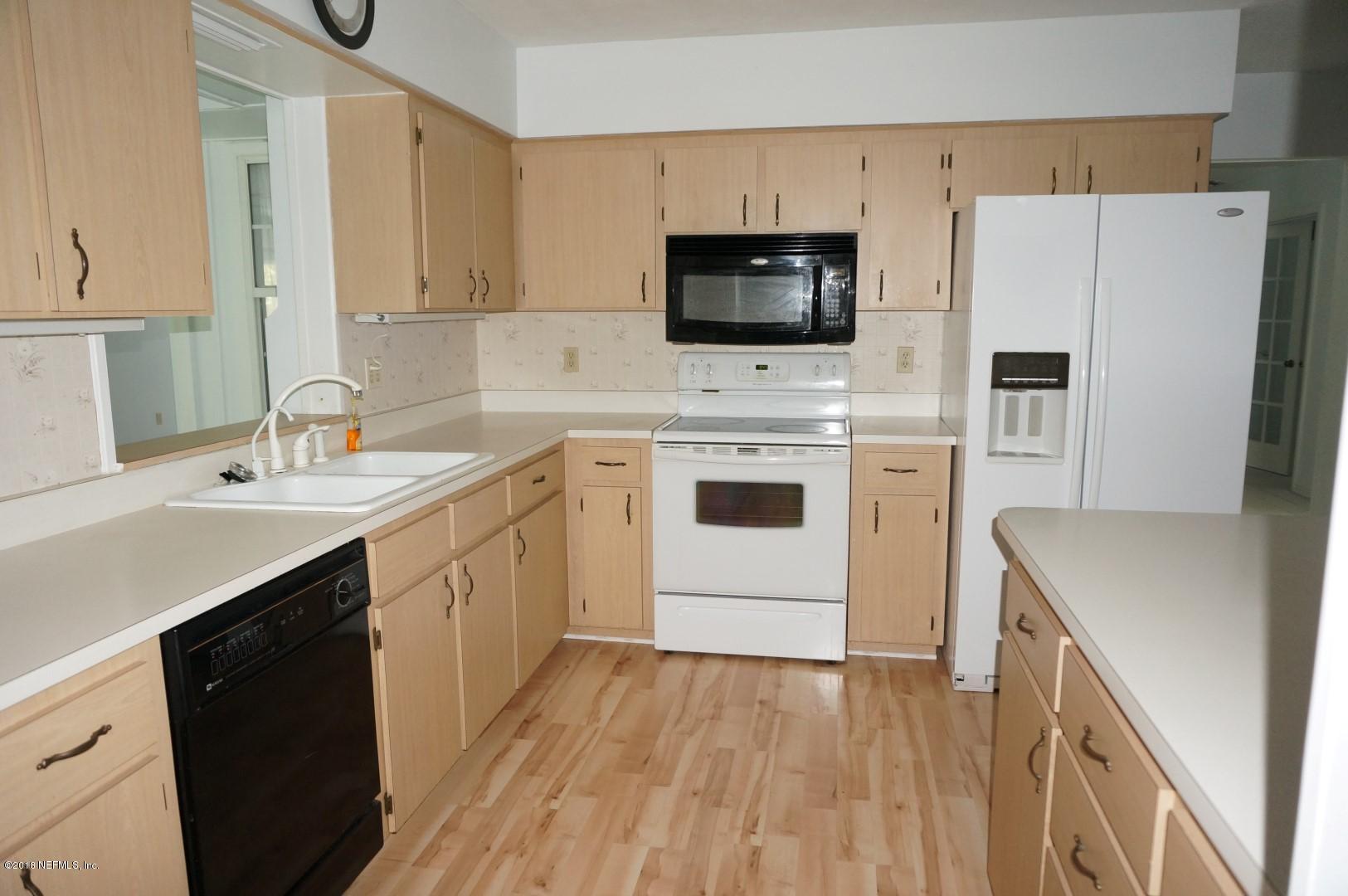6511 Brooklyn Bay Road Keystone Heights, FL 32656 - Photo 8 of 25 a kitchen with a sink a microwave a refrigerator and white cabinets