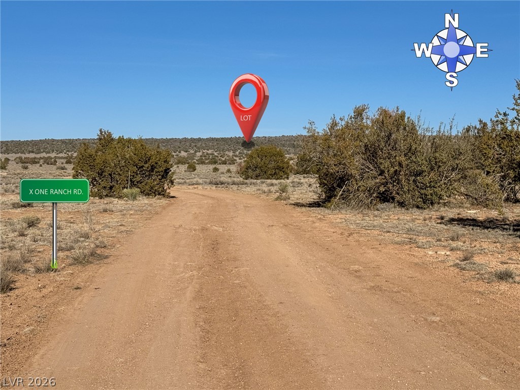 0 X-One Ranch Road Seligman, AZ 86337 - Photo 9 of 9 A spacious lot featuring a rural dirt road entrance, set against a wide-open landscape.