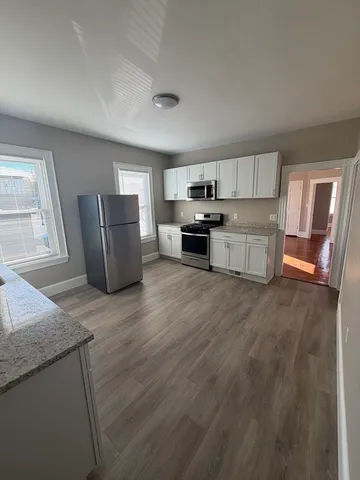 a kitchen with granite countertop a refrigerator and wooden cabinets