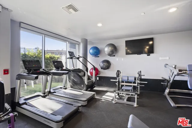 a living room with stainless steel appliances granite countertop furniture a refrigerator and a potted plant