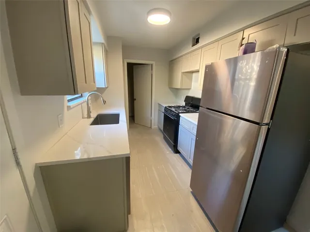 a kitchen with stainless steel appliances a refrigerator a sink a stove and white cabinets