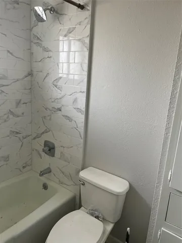a white toilet sitting next to a bath tub