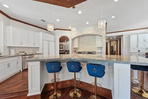 a kitchen with stainless steel appliances granite countertop a sink a stove a dining table and chairs