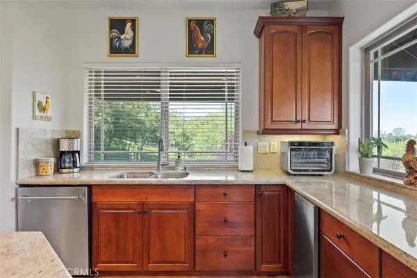 a kitchen with kitchen island granite countertop a sink stove and wooden cabinets