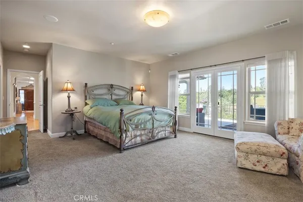 a spacious bedroom with a bed a chandelier and large windows