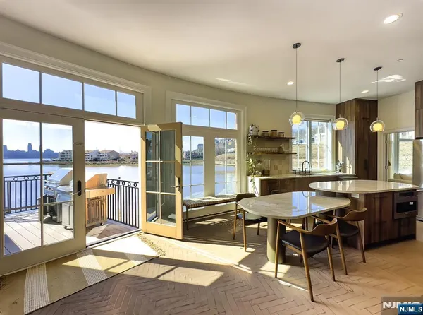 a dining hall with stainless steel appliances granite countertop a stove a sink a dining table and chairs with wooden floor