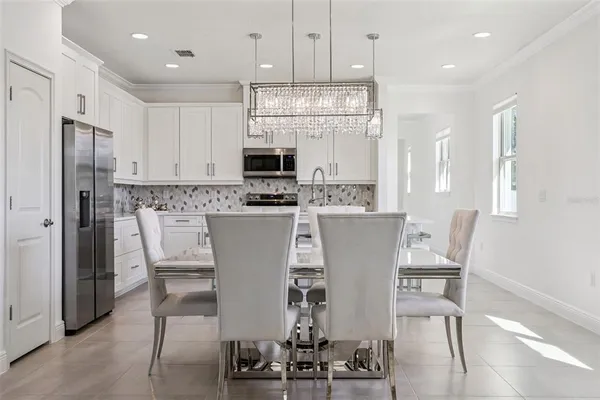 a kitchen with kitchen island a dining table chairs stainless steel appliances and cabinets