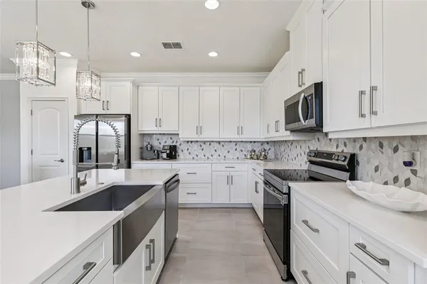 a kitchen with white cabinets sink and stainless steel appliances